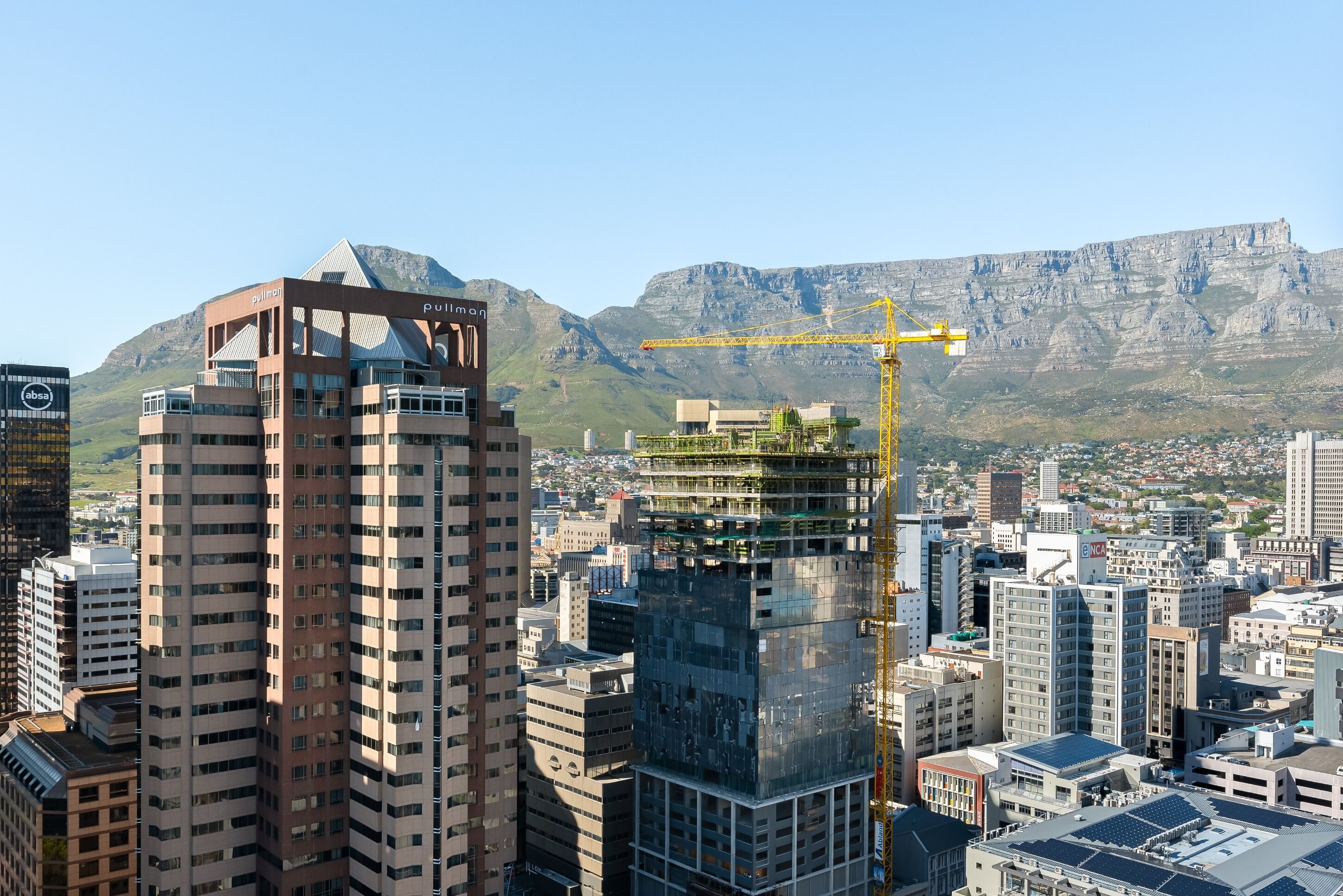 A high-rise building with a distinctive triangular top and a construction crane nearby.