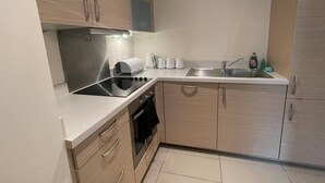 Una cocina moderna con estufa, horno y lavaplatos integrados. Hay armarios con manijas, una encimera y un salpicadero.