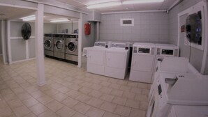 A laundry room with multiple washing machines and dryers, a clock, and a fire extinguisher. - Cute Condo close to Coligny Beach (Hilton Head Island)