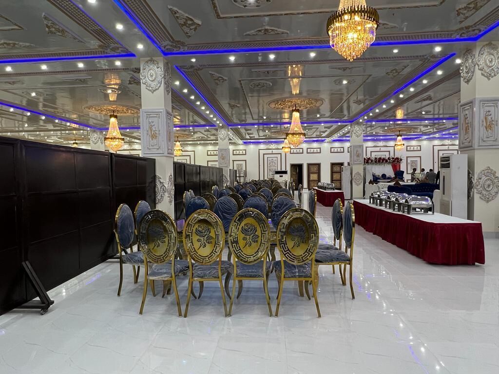 A banquet hall with rows of round tables, blue upholstered chairs, and gold detailing.