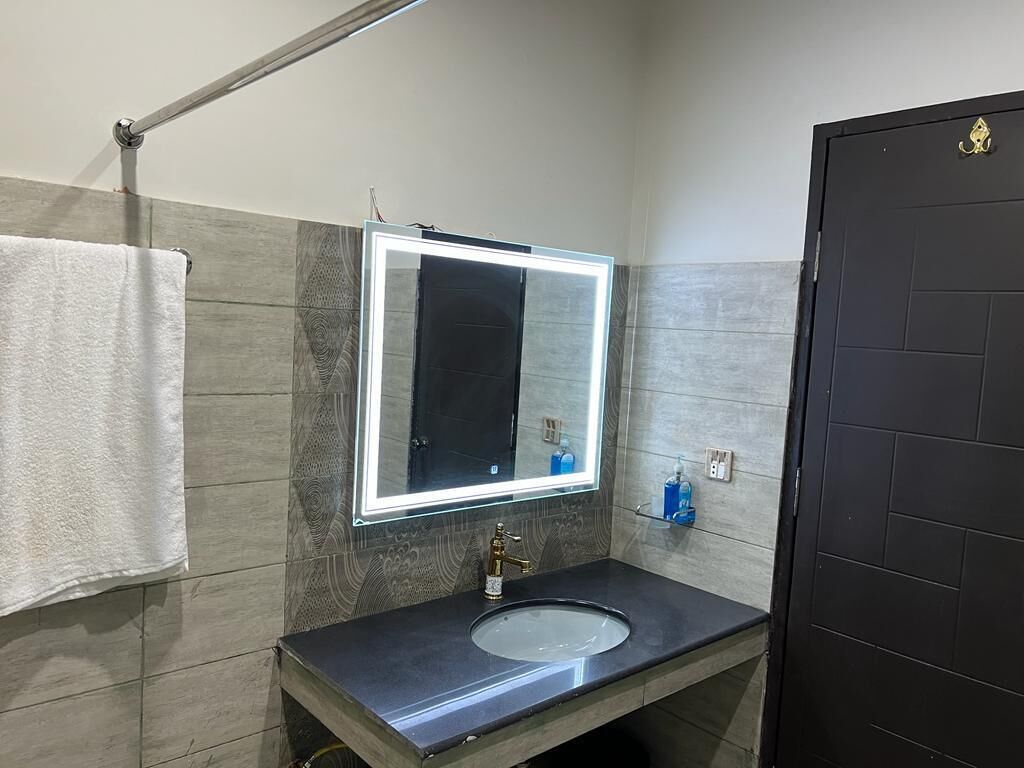A modern bathroom with a vanity, a large mirror, and a towel hanging on the wall.