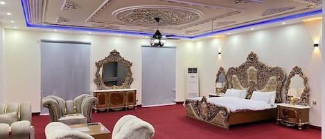 A luxurious bedroom with a large bed, ornate headboard, and a red carpet.