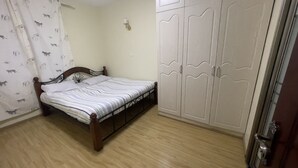 Une chambre à coucher avec un lit en bois, une armoire et un rideau orné de motifs animaliers.