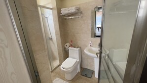 Une salle de bain comprenant des toilettes, une douche, un lavabo et un espace de douche séparé par des parois en verre.
