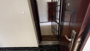 Un escalier étroit mène à une pièce dont le sol est recouvert de carreaux et qui est dotée d’une porte avec un portail en métal.