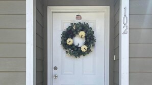 A white front door with a wreath, a "hello" mat, and a mailbox. - Comfortable Coastal 2 BDRM home - 5 mins to downto (saint marys)