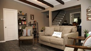 Ein gemütliches Wohnzimmer mit einer Couch, einem Sessel und einem Bücherregal.