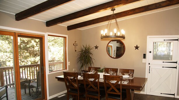 Ein Esszimmer mit einem Holztisch, Stühlen und einer Chandelier. Eine Schiebetür aus Glas führt zu einer Terrass.