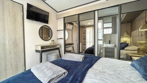 A modern hotel room with a bed, a desk, a mirror, and a television. - 2 bedroom accommodation in Peterhead (Peterhead)