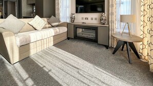 A modern living room with a sofa, a flat-screen TV, a coffee table, and a lamp. - 2 bedroom accommodation in Peterhead (Peterhead)