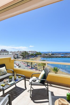 Ein Balkon mit Meerblick, ein Tisch mit einer Pflanze und ein Stuhl.