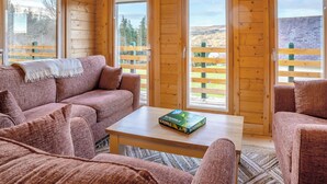 A wooden cabin interior with a sofa, a table, and a game box. - 2 bedroom accommodation in Garnant Ammanford (Garnant Ammanford)