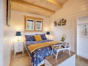 A bedroom with a bed, bedside tables, a window, and a wall-mounted drying rack.