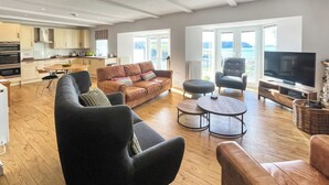 En moderne stue med sofa, lænestole, sofabord og fjernsyn.