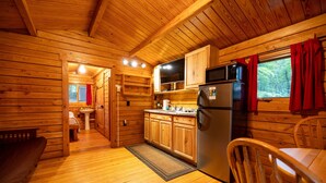 Ein Holzblock-Interieur mit Küche, Essbereich und einem sichtbaren Badezimmer.