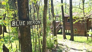 Eine Holzhütte mit der Aufschrift 'BLUE HERON', umgeben von Bäumen und einer Holzterrasse.