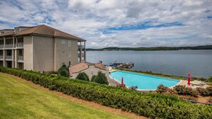 A hotel with a swimming pool, a dock, and a view of a lake.