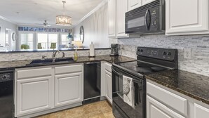 A modern kitchen with white cabinetry, a black stove, and a microwave.