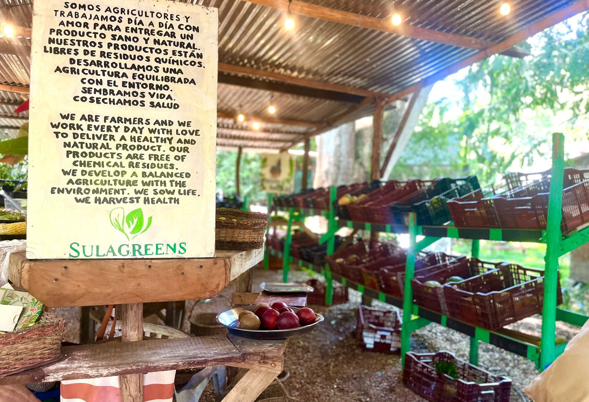 A market stall with crates of produce and a sign promoting natural farming practices.