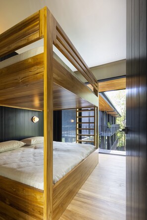 Quarto moderno com uma cama de solteiro embutida de madeira, uma mesa de cabeceira e vista para o exterior.