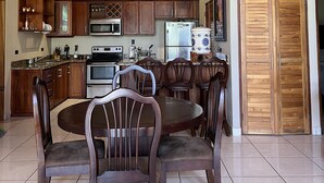 Un'ampia cucina con mobili in legno, una zona pranzo con un tavolo rotondo e sedie, e una ventola a soffitto.