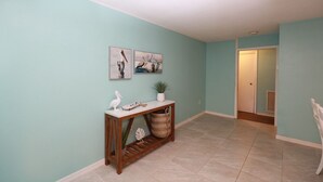 A hallway with teal walls, a wooden console table with decorative items, and a door leading to another room.