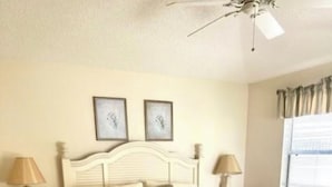 Un dormitorio con una cama grande, dos mesitas de noche y un ventilador de techo.
