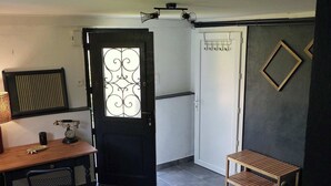 A room with a desk, chair, and a small bench. There is a door with a decorative glass panel, a coat rack, and a wall-mounted mirror. - Maison à la Montagne Avec la vue sur le Montcalm Avec son Jardin Clôturé (Auzat)