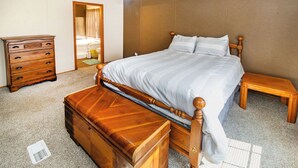 Een slaapkamer met een houten bed, een dressoir en een nachtkastje.