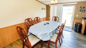 Een eethoek met een ronde tafel, houten stoelen en een plafondventilator.