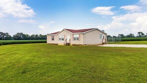 Een gelijkvloers huis met een rood dak, een voortuin en een kleine trap naar de ingang.
