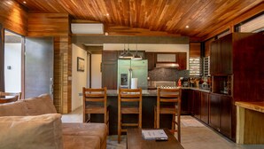 A modern kitchen with wooden ceiling, built-in cabinets, and a central island with bar stools.