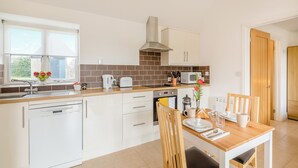 Eine moderne Küche mit weißen Schränken, einer Holz Arbeitsplatte, einem eingebauten Backofen und einem Essbereich mit Holztisch und Stühlen.