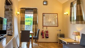 Een kamer met een stenen muur, een tafel met stoelen, een bank, een kaart aan de wand en een brandblusser.