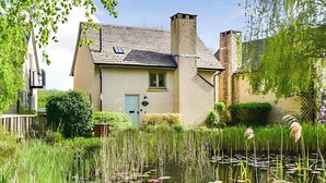 A house with a chimney, a blue door, and a pond with lily pads. - 3 bedroom accommodation in Somerford Keynes (Somerford Keynes)