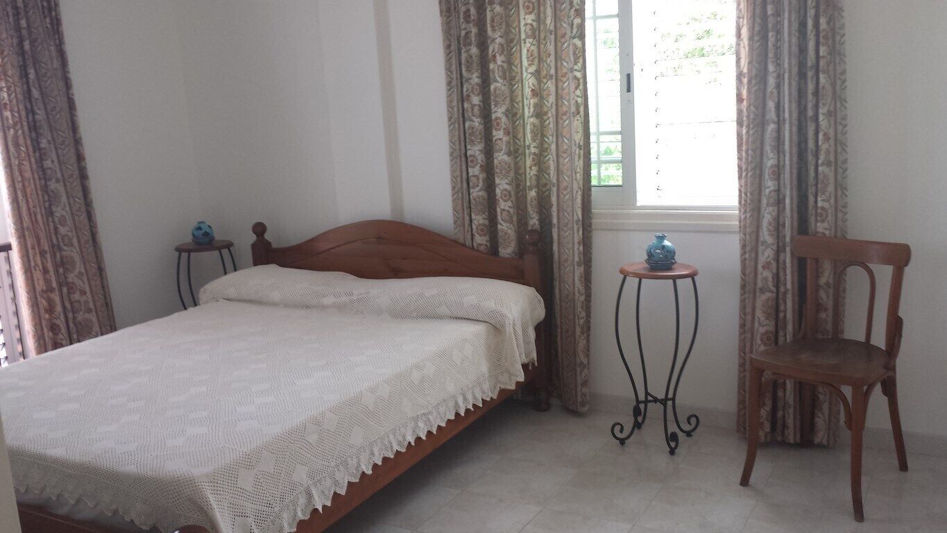 Une chambre à coucher avec un lit, une chaise et deux petites tables.