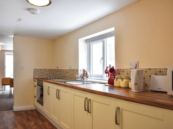 A kitchen with a wooden countertop, a window, and a Prolex water dispenser.