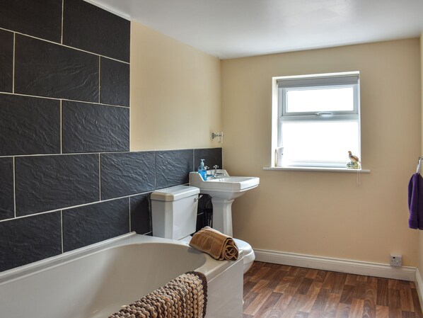Une salle de bain avec une baignoire, un lavabo et une fenêtre.