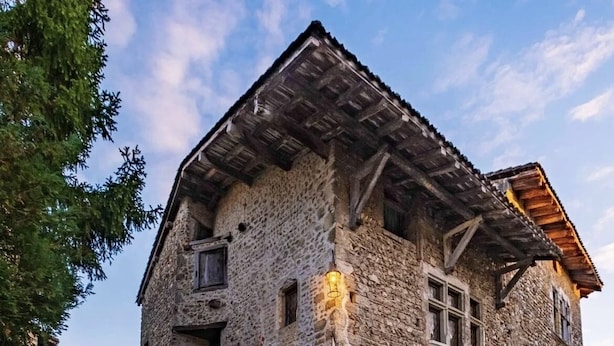 Un edificio de piedra con techo inclinado, vigas de madera y un patio empedrado.