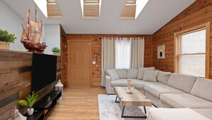 Een moderne woonkamer met houten wanden, een grote televisie, een bank, een salontafel en een scheepsmodel.