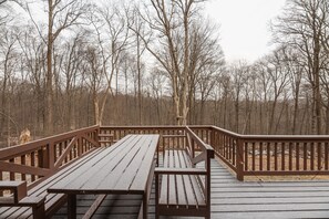 Een houten terras met bankjes en leuningen, omgeven door bomen.