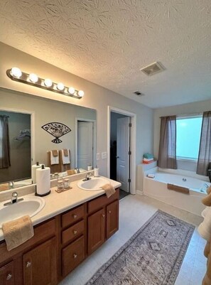 A bathroom with a double sink vanity, a large mirror with lights, a bathtub, and a view of the sky. - Sleeps 8: King sized bed - Home away from home, yet close to everything! (Douglasville)