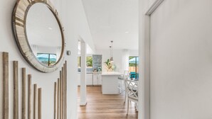 A modern kitchen with a central island, wooden vertical accents on the wall, and a view of the outdoors through large windows. - Beach & City Oasis: Moments from Siesta Key Beach (Sarasota)