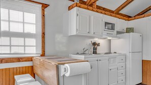 Een moderne keuken met witte kasten, een houten aanrechtblad en een ingebouwde magnetron.