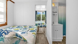 Een compacte slaapkamer met twee bedden, een kleine badkamer en uitzicht op de omgeving.
