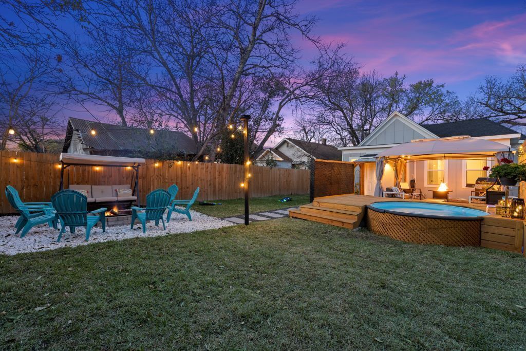 Ein Garten mit Holzterrasse, Sitzgelegenheiten im Freien, einem Whirlpool und Lichterketten.