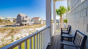 A beachfront property with a covered porch, outdoor seating, and a view of neighboring houses. - Awesome Beach House, Private Pool, Gulf View (Navarre)