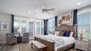 A bedroom with a large bed, two chairs, a bench, a nightstand, and a ceiling fan. - Awesome Beach House, Private Pool, Gulf View (Navarre)