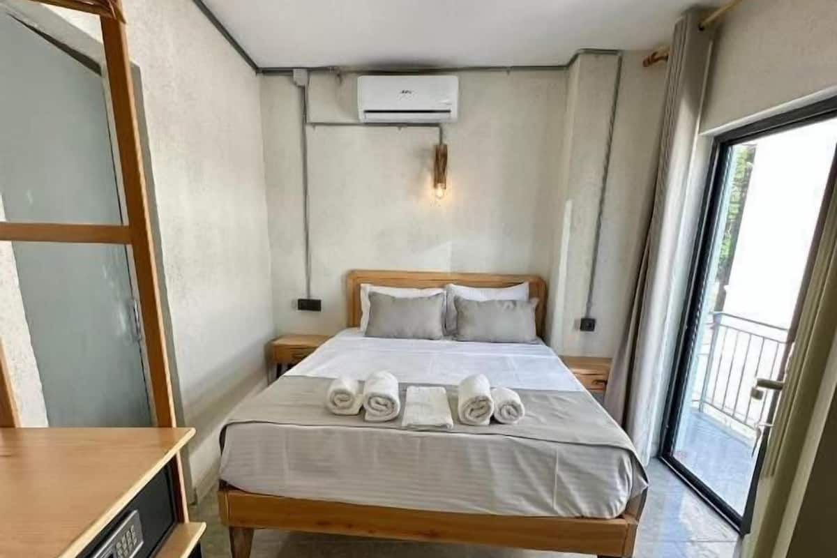 A hotel room with a bed, a TV, a small table, and a balcony.