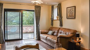 A cozy living room with a brown leather sofa, a dining table with chairs, a glass of wine, and a painting on the wall. - Intimate and inviting, this couples retreat is a cosy haven for two. (South Kilvington, near Thirsk)